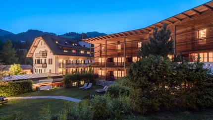 Hotel Ostaria Posta © Watzek Photografie Beleuchtete Hotelgebäude und Garten bei Dämmerung in den Bergen