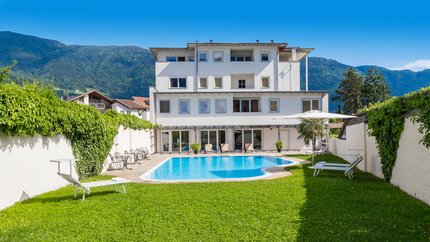 Modernes weißes Gebäude mit Schwimmbad und Bergen im Hintergrund