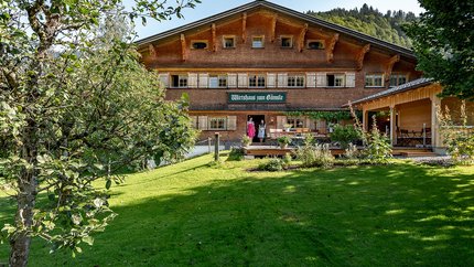 Traditionelles Gasthaus in einer grünen Landschaft mit zwei Personen an der Tür