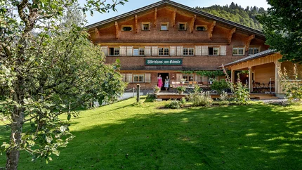 Gämsle Hotel, Wirtshaus & mehr © Raffael F. Lehner Traditionelles Gasthaus in einer grünen Landschaft mit zwei Personen an der Tür