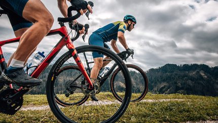 Zwei Radfahrer fahren auf einem Bergpfad bei bewölktem Himmel