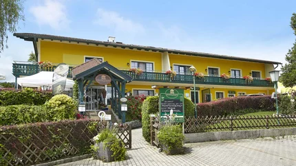 Landgasthof Krumbacherhof © Wiener Alpen Croy Gelbes Hotel mit grünem Eingang und Blumen an der Terrasse