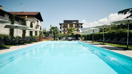 Traminerhof © Manuel Ferrigato Großer Pool mit Liegestühlen und Sonnenschirmen vor einem modernen Gebäude