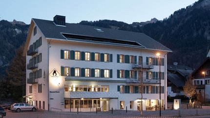 Hotelgebäude mit beleuchteten Fenstern am Abend in bergiger Umgebung