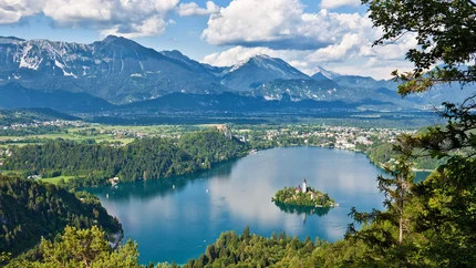 Julische Alpen © Jost Gantar - www.slovenia.info See mit Insel und Berglandschaft bei klarem Himmel