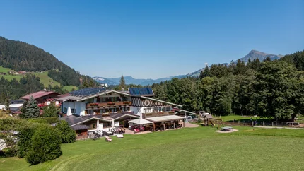Alpenhotel Landhaus Küchl © Michael Küchl Berghotel mit Solarpanels umgeben von Wiesen und Bergen bei klarem Himmel