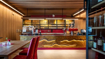 Moderner Barbereich mit Holzvertäfelung und roten Sitzstühlen