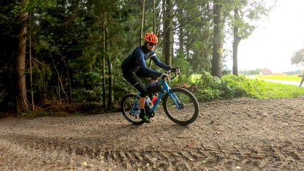 Radfahrer mit orange Helm fährt auf Waldweg