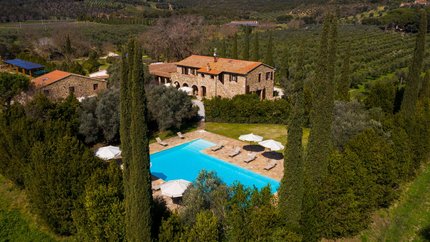 Steinhaus mit Pool umgeben von Bäumen in einer grünen Hügellandschaft