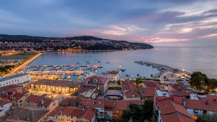 Abendlicher Blick auf Hafen und Stadt mit beleuchteten Gebäuden am Wasser