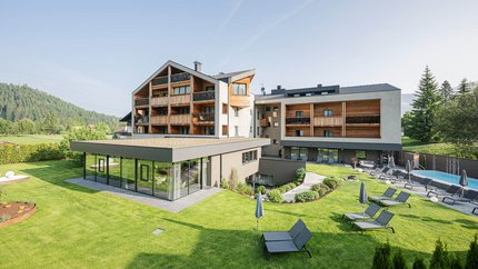 Modernes Hotel mit Garten, Pool und Sonnenliegen in sonniger Landschaft